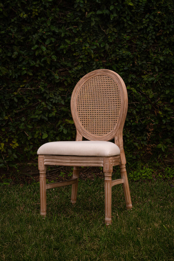 Light wood cane-back chair with off-white cushion.