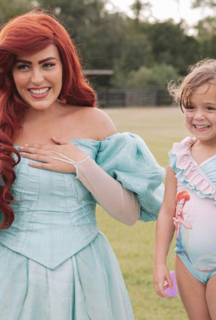 Ariel-themed kids' party: a girl in an Ariel costume with a young girl.