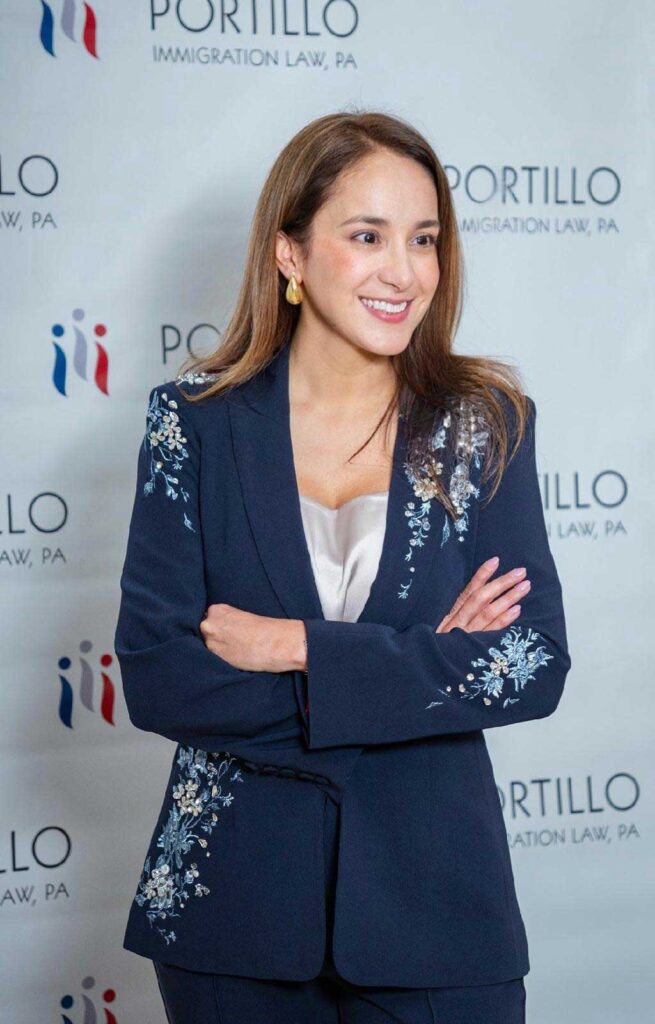 Portillo Law Firm private event: Woman in navy blazer with floral embroidery, arms crossed.