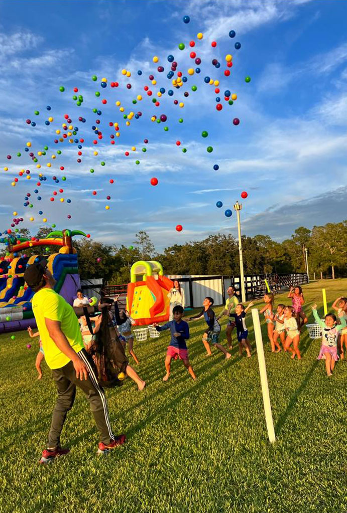 Kids' ball toss party: Colorful balls fly as children play outdoors.